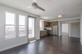Located at 318 W Wilson Ave in Glendale, California, this modern single-floor residence offers a well-designed open-concept layout that seamlessly connects the living area and kitchen. Rich dark hardwood flooring runs throughout the main living spaces, complementing the clean, contemporary aesthetic defined by crisp white walls and smooth ceilings.

The kitchen is outfitted with warm wood-toned cabinetry extending to the ceiling for ample storage, stainless steel appliances including a gas range, microwave, dishwasher, and refrigerator, along with a double-basin sink set into light countertops. A track lighting system and a window provide both task illumination and natural light.

The living area is bright and open, benefiting from large windows and a glass door that lead to a private balcony overlooking the Glendale cityscape. A ceiling fan adds comfort to this generously proportioned space. The bedrooms feature plush carpeting, ceiling fans, and large windows that frame urban views, while walk-in closet space provides practical storage. The bathroom is finished in a clean, modern style with a soaking tub and shower combination, wood-toned vanity cabinetry, and white tile surround, completing this well-appointed urban residence.