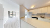 This well-appointed 2-bedroom, 2-bathroom residence offers a thoughtfully designed single-level layout that maximizes both space and natural light. The open-concept living and dining areas are anchored by expansive floor-to-ceiling windows that wrap around the corners of the unit, flooding the interior with daylight and framing impressive cityscape views. Light-toned hardwood flooring runs throughout, complementing the clean, neutral palette of the white walls and ceilings.

The kitchen is efficiently laid out with a peninsula countertop, crisp white cabinetry, a subway tile backsplash, and stainless steel appliances including a full-size range and refrigerator. It connects seamlessly to the living areas, making it ideal for everyday living and entertaining.

The primary bedroom is generously sized with large windows overlooking the urban skyline, while the second bedroom also benefits from natural light and city views. Both bathrooms are finished with tile flooring and full soaker tub-and-shower combinations — one featuring rich teal stacked tile surround with elegant wall sconces, and the other with neutral large-format tile and classic fixtures.

Throughout the residence, the consistent use of light materials, abundant natural light, and urban panoramas create a bright, airy, and contemporary living environment.