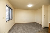 This efficient 1-bedroom, 1-bathroom unit is thoughtfully laid out across a single floor, offering a practical and functional living space. The layout includes a kitchen, bedroom, hallway, and bathroom, making the most of every square foot available.

The kitchen is well-equipped with warm oak-toned cabinetry, ample upper and lower storage, a gas range with an over-the-range microwave, a full-size refrigerator, and a sink. Light-toned tile-style flooring runs throughout the kitchen, and a window provides natural light. A baseboard heating unit ensures comfort year-round.

The living and entry area features light hardwood-style flooring, a large window overlooking a tree-lined exterior, and a baseboard heater. The carpeted bedroom offers a comfortable retreat, complete with a wall-mounted air conditioning unit, a window with natural light, and a baseboard heater for climate control. An open closet with a full-width hanging rod provides convenient storage, and the textured ceiling is consistent throughout the unit.

The bathroom is clean and functional, featuring a full-size soaking tub with an overhead shower, a toilet, and a bright white surround. Wood-toned interior doors and trim add a warm contrast to the neutral cream-colored walls found throughout the space.
