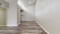 Located in Houston, TX 77090, this single-story residence showcases a consistent, modern aesthetic carried throughout by durable wood-look plank flooring in a warm gray-brown tone. Neutral-toned walls and white baseboards create a clean, cohesive look across all rooms.

The galley-style kitchen is outfitted with white shaker cabinetry, light countertops, a subway tile backsplash, an undermount sink with brushed nickel fixtures, and stainless steel appliances. High clerestory windows above the kitchen allow natural light to filter into the adjoining living area, which also benefits from vaulted ceiling height that enhances the sense of openness.

The bedrooms are well-proportioned, each featuring window blinds for light control and ceiling fans where applicable. A long hallway with textured walls connects the private sleeping areas to the rest of the home, providing a clear and functional layout.

Two full bathrooms include tub-shower combinations with white tile surrounds, standard fixtures in brushed nickel, and wood-look flooring that ties seamlessly to the rest of the home. One bathroom features a white vanity with storage. Throughout, the space maintains a clean, move-in-ready presentation with a practical, understated design.