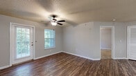 Located at 500 Kraft Street in Clarksville, Tennessee, this one-bedroom, one-bathroom unit offers a practical and comfortable single-floor layout. The combined kitchen and living area serves as the heart of the home, with wood-style plank flooring flowing throughout the main living spaces. The kitchen features light wood cabinetry with ample upper and lower storage, white appliances including a refrigerator, range, and dishwasher, a double-basin sink, and a peninsula counter that separates the kitchen from the living area. The living room is bright and airy, with a ceiling fan, a large window, and a glass door that opens to a private outdoor entry area, allowing natural light to fill the space. The bedroom is carpeted for comfort, includes a ceiling fan, a window with outdoor views, and a generously sized closet. The bathroom is well-appointed with a wood-toned vanity, a large mirror, and additional tall cabinetry for storage. The unit also includes a dedicated laundry area for added convenience. Textured ceilings and neutral gray walls throughout create a clean, move-in-ready aesthetic suited for everyday living.