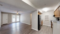 This well-appointed 3-bedroom, 2-bathroom single-floor residence at 6355 Oakley Rd in Union City, GA offers a comfortable and functional layout across a generous floor plan. The open living area is bright and welcoming, featuring durable wood-look flooring, neutral warm-gray walls, a textured ceiling, and a ceiling fan that runs throughout the main living spaces. French doors in the living room invite natural light and provide access to a private balcony overlooking a tree-lined exterior, adding a touch of greenery to everyday living. The galley-style kitchen is efficiently designed with warm wood cabinetry, light countertops, built-in shelving, and black appliances including a refrigerator, range, and dishwasher. Each of the three bedrooms offers ample space, ceiling fans, and easy access to the hallway. The spacious primary bedroom includes a dedicated walk-in closet with built-in shelving. Both bathrooms are finished with wood-look flooring, warm wood vanities, and light countertops. One bathroom features a soaking tub, while the other includes a vanity with a large mirror. A hallway connects all rooms cohesively, completing this practical and comfortable home.