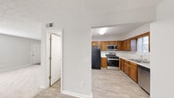 Located in Marietta, GA, this two-story home offers a practical and well-organized layout spread evenly across two floors. The main level features a carpeted living room filled with natural light from a window with blinds, transitioning to a kitchen equipped with warm oak cabinetry, white countertops, and stainless steel appliances including a gas range, over-the-range microwave, and a black refrigerator. Light wood-look flooring runs through the kitchen, while a hallway connects to a full bathroom featuring a tub-shower combo with tile surround, a vanity with mirror, and a built-in linen closet with shelving. A carpeted staircase with white railings leads to the upper level, where the spacious primary bedroom features plush carpet, natural light, and an open closet with built-in shelving. The second bedroom is similarly carpeted and bright. A second full bathroom with a vanity and mirror serves the upper floor. Textured ceilings are consistent throughout the home, and neutral gray-toned walls provide a clean, versatile backdrop. Two dedicated closets add valuable storage. The layout is efficient and functional, making this Marietta home a well-rounded two-story residence.