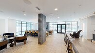 Located at 800 Van Cliburn Way in Fort Worth, Texas, this elegantly appointed clubroom offers a generously sized, single-floor amenity space designed for both social gatherings and relaxed lounging. The interior is anchored by a striking herringbone-patterned hardwood floor that flows throughout, complemented by crisp white ceilings with recessed and pendant lighting, including a dramatic ring chandelier that serves as a focal point above the central lounge area.

A bold textured brick column divides the open-plan layout, creating natural zones within the space. The main lounge features plush sectional and accent seating arranged around a glass coffee table, while a secondary lounge area showcases intimate booth-style banquettes set against richly tiled copper-toned accent walls, illuminated by pendant lights. Dark velvet lounge chairs and sculptural furniture add depth and sophistication throughout.

A fully equipped kitchenette includes stone countertops, dark cabinetry, a built-in oven, and dual wall-mounted televisions backed by polished marble tile. A long communal dining table with a sculptural centerpiece anchors an adjacent gathering area. Floor-to-ceiling windows on multiple walls flood the space with natural light and offer views of the surrounding outdoor patio and community terrace, accessible through a set of full-glass French doors.