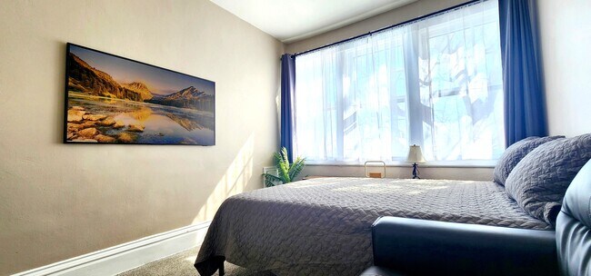 Primary Bedroom -Enjoy a 55” Samsung Frame TV and ample natural light through the oversized windows. - 822 E 4th St