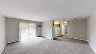 Located at 6 Sussex Dr in Newark, Delaware, this single-floor, one-bedroom, one-bathroom unit offers a practical and comfortable layout across a well-utilized floor plan. The living room is a generous, open space finished with neutral-toned carpet and light gray walls, offering a bright and airy atmosphere. A sliding glass door with vertical blinds leads to an outdoor patio area, filling the room with natural light and providing pleasant green views. A wall-mounted air conditioning unit and baseboard heating ensure year-round comfort. The galley-style kitchen is efficiently arranged with warm honey-toned wood cabinetry lining both sides, a white coil-top electric range, a full-size white refrigerator, a stainless steel sink, and tile backsplash accents. Stone-look tile flooring and a window overlooking the outdoors add both practicality and light to the space. The spacious bedroom features soft carpeting, a window with natural views, baseboard heating, and notably, two side-by-side bi-fold closets that provide ample storage. The bathroom is clean and bright, outfitted with a full tub-shower combination, chrome fixtures, and a frosted privacy window. Throughout the unit, neutral tones and consistent finishes create a cohesive and functional living environment.