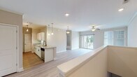 Located at 5811 Garden Village Ct in Greensboro, NC, this single-floor residence offers a well-designed, open-concept layout that seamlessly connects the kitchen, dining, and living areas. Light hardwood-style flooring flows throughout the main living spaces, complemented by neutral toned walls and crown molding that lend a clean, polished look.

The kitchen is a functional highlight, featuring white cabinetry with contemporary hardware, granite countertops, a peninsula with pendant lighting overhead, and stainless steel appliances including a refrigerator, microwave, and dishwasher. A ceiling fan with a light kit anchors the living room, which benefits from abundant natural light streaming through a sliding glass door that opens onto a private outdoor balcony with outdoor views.

The bedrooms are carpeted for comfort, each equipped with a ceiling fan and windows fitted with blinds for light control and privacy. At least one bedroom features access to a walk-in closet. The bathroom is appointed with granite counters, a combination tub and shower with tiled surround, and brushed nickel fixtures throughout.

Overall, the space presents a bright, move-in-ready interior with consistent finishes, practical storage, and a comfortable, well-connected floor plan suited for everyday living.