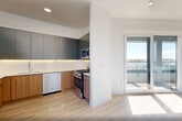 This thoughtfully designed two-story residence in Bayonne, NJ offers a bright, modern living experience across two well-proportioned floors. Light hardwood flooring flows throughout, complementing the clean white walls and recessed lighting that give every room an airy, contemporary feel.

The lower level features an open-concept kitchen and living area flooded with natural light through expansive floor-to-ceiling sliding glass doors that lead directly to a private balcony with open views of the surrounding neighborhood. The kitchen is outfitted with two-tone cabinetry—warm wood lower cabinets paired with sleek matte upper cabinets—and a full suite of stainless steel appliances, including a gas range, dishwasher, microwave, and refrigerator, all set against crisp white countertops.

The upper floor houses two well-sized bedrooms, each featuring large windows with sweeping outdoor views and generous closet space. The two bathrooms offer distinct, stylish finishes: one showcases dramatic marble-effect wall tile with a floating vanity and a backlit round mirror, while the other features a soaking tub surrounded by glossy gray subway tile. A dedicated laundry area and multiple closets throughout add practical convenience to this polished, move-in-ready home.