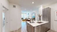 Located at 2900 Brighton Blvd in Denver's vibrant RiNo neighborhood, this well-appointed 1-bedroom, 1-bathroom residence offers a thoughtfully designed open-concept floor plan. Light wood-tone flooring flows throughout, complemented by crisp white walls and recessed lighting that create a clean, contemporary aesthetic.

The kitchen serves as a central hub, featuring wood-grain cabinetry, quartz countertops, stainless steel appliances including a refrigerator, microwave, and dishwasher, and a peninsula with bar seating — ideal for both cooking and casual dining. The open layout allows the kitchen to connect seamlessly to the dining and living areas, where large windows invite abundant natural light and offer views of the surrounding neighborhood.

The living room provides a comfortable, well-proportioned space with a large window and sliding glass access. The bedroom is a serene retreat with a generous window, closet access, and room for a full-sized furniture arrangement. The bathroom includes a full soaking tub with marble-style tile surround, offering a refined finish. A dedicated laundry area with a stacked Whirlpool washer and dryer adds everyday convenience. This residence delivers a complete, functional living experience in a modern Denver setting.