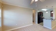 Located at 755 CL Tart Cir in Fayetteville, North Carolina, this single-floor residence offers a practical and well-appointed living environment. The open layout connects the main living area to the kitchen, creating a cohesive and functional flow throughout the space. The living area features light-toned flooring, neutral beige walls, and crisp white crown molding that adds a clean, finished look to the interior. A ceiling fan is installed overhead, contributing to both comfort and air circulation. The kitchen is equipped with dark espresso cabinetry, black appliances including a refrigerator and range, and dark stone countertops that provide a striking contrast to the lighter tones found throughout the rest of the space. A glimpse beyond the main living area reveals a laundry area, adding to the home's practical amenities. The consistent use of crown molding throughout ties the spaces together and gives the interior a cohesive, polished character. Overall, the residence presents a straightforward and functional design suited for comfortable everyday living.