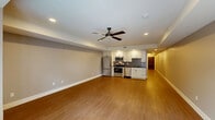 Located at 112 Walnut Blvd in Rochester, MI, this thoughtfully designed one-bedroom, one-bathroom unit offers a comfortable and modern living experience across a single floor. The open-concept layout seamlessly connects the living room, dining area, and kitchen into one cohesive, well-lit space. Warm hardwood-style flooring flows throughout, complemented by neutral gray walls and recessed lighting, including a ceiling fan that anchors the main living area. The kitchen is well-appointed with white shaker cabinetry, dark granite countertops, a gray subway tile backsplash, and a full suite of stainless steel appliances including a refrigerator, range, microwave, and dishwasher. A long hallway with recessed lighting connects the main living space to the private quarters, offering access to two closets and a dedicated laundry area. The bedroom features plush carpet flooring and a clean, neutral palette. The bathroom is finished with large-format tile and a glass-enclosed walk-in shower with dark bronze fixtures. A private balcony provides outdoor space with views of the surrounding neighborhood. A utility room and additional unclassified room round out this well-equipped unit.