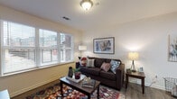 Located at 2501 S 4th St in Louisville, Kentucky, this single-floor unit offers a thoughtfully designed layout with consistent hardwood-style flooring flowing throughout every room. The living area is welcoming and well-lit, featuring large windows with blinds that frame views of the surrounding neighborhood and allow abundant natural light to fill the space. The kitchen is efficiently arranged with warm-toned wood cabinetry, granite-style countertops, and black appliances including a dishwasher and range, positioned conveniently near the entry door. The primary bedroom provides a comfortable retreat with ample natural light from a large window, hardwood-style flooring, and neutral wall tones that create a calm atmosphere. A second bedroom offers versatility, featuring a window with outdoor views and space well-suited for both sleeping and a dedicated work area with a desk setup. The full bathroom is clean and bright, finished with wood-toned cabinetry, a tub-shower combination, and hardwood-style flooring that ties seamlessly into the rest of the unit. Throughout the space, neutral walls, consistent flooring, and thoughtful layout choices combine to create a cohesive and functional living environment.