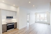 Located at 10015 113 St NW in Edmonton's vibrant Oliver neighbourhood, this thoughtfully designed two-bedroom, two-bathroom unit offers a clean, modern aesthetic throughout. Light-toned engineered hardwood flooring flows seamlessly across the entire space, complemented by crisp white walls and recessed lighting that create a bright, airy atmosphere.

The open-concept living and kitchen area forms the heart of the unit. The kitchen is well-appointed with two-tone cabinetry — white upper cabinets paired with woodgrain lower cabinets — along with light quartz countertops, a stainless steel appliance package including a refrigerator, electric range, built-in microwave, and dishwasher. The living area extends toward a large picture window that frames sweeping views of the Edmonton skyline and surrounding neighbourhood.

Both bedrooms are comfortably sized with large windows that bring in generous natural light and offer city views. Three closets provide ample storage throughout the unit. The bathrooms are finished in a clean, contemporary style, featuring marble-look tile surround in the tub-shower combination. An in-unit laundry area adds everyday convenience. The overall ambiance is modern, clean, and move-in ready.