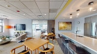 Located at 680 N Clark St in Chicago's River North neighborhood, this amenity floor offers a comprehensive range of communal spaces designed to support both relaxation and recreation. The layout is open and well-connected, with glass-partitioned walls allowing natural light to flow between zones while maintaining visual separation.

The lounge areas are furnished with contemporary swivel chairs, leather sofas, and patterned carpeting in warm gold and neutral tones. A standout feature is the stone-accent fireplace wall with a mounted flat-screen TV, creating a cozy focal point. Yellow accent walls and curated artwork add color and personality throughout.

A dedicated game room includes a foosball table, shuffleboard, high-top seating, and additional lounge chairs arranged around a large TV with city views through wide windows. The fully equipped kitchen features stainless steel appliances, sleek gray cabinetry, a large white quartz island with bar seating, and decorative ceiling lighting.

The fitness center is well-appointed with treadmills, ellipticals, and other cardio equipment, benefiting from natural light and mounted TVs. A spacious on-site laundry facility rounds out the floor, offering multiple commercial-grade washers and dryers in a clean, utilitarian space.