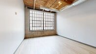 Located at 470 Market Ave SW in the heart of Grand Rapids, Michigan, this one-bedroom, one-bathroom urban loft showcases a compelling blend of industrial character and modern finishes. The open layout is unified by light-toned luxury vinyl plank flooring throughout, lending a clean and cohesive aesthetic to the space.

The main living area features striking exposed wood beam ceilings with visible ductwork, a hallmark of loft-style architecture that adds warmth and raw texture to the contemporary design. The galley-style kitchen is well-appointed with stainless steel appliances — including a French-door refrigerator, electric range, and over-the-range microwave — complemented by gray cabinetry, white quartz countertops, a subway tile backsplash, and a deep single-basin sink with a matte black faucet. A sliding barn door adds a stylish, space-conscious touch.

The bedroom is a compact, efficiently designed retreat with neutral walls and consistent flooring. The bathroom is finished with floor-to-ceiling white subway tile in the tub/shower surround, dark slate-toned floor tile, and sleek matte black fixtures and hardware, creating a sharp, modern contrast. This loft offers an ideal urban living experience in one of Grand Rapids' vibrant downtown neighborhoods.
