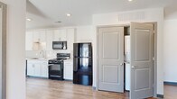 Located at 366 E Broad St in the heart of Columbus, Ohio, this single-floor unit offers a thoughtfully designed layout with contemporary finishes throughout. The kitchen is a standout feature, boasting crisp white cabinetry extending to the ceiling, a classic white subway tile backsplash, light wood-look flooring, and a full suite of black appliances including a range, over-the-range microwave, dishwasher, and refrigerator. A dedicated in-unit laundry closet with a stacked washer and dryer is conveniently accessible from the kitchen area. The bedroom features plush carpeting and a large floor-to-ceiling window that frames views of the surrounding Columbus cityscape, flooding the room with natural light. The bathroom is equally well-appointed with white vanity cabinetry and a striking oversized window offering expansive urban views, including prominent downtown Columbus landmarks. A walk-in closet provides generous storage. The unit also includes a recessed electrical panel and recessed lighting throughout the main living areas. The clean, neutral palette and modern design elements create a bright, airy ambiance that complements the dynamic downtown Columbus location.