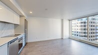 Located in the heart of downtown Montréal on Boulevard René-Lévesque Ouest, this modern one-bedroom, one-bathroom unit offers a thoughtfully designed layout with clean, contemporary finishes throughout. Light wood laminate flooring runs seamlessly across the entire space, complementing the crisp white walls and creating a bright, cohesive aesthetic.

The open-concept living area is a standout, anchored by expansive floor-to-ceiling windows that flood the space with natural light and frame impressive views of the surrounding Montréal cityscape. The kitchen is integrated into the living space and features stainless steel appliances, including a refrigerator and oven, set against white cabinetry.

The bedroom offers its own generous window with city views, providing a quiet retreat with ample natural light. A closet is conveniently situated nearby, offering dedicated storage.

The bathroom is finished in a modern style with large-format grey stone-effect tiles lining the walls and floor. A glass-enclosed walk-in shower with a built-in bench, a wall-mounted vanity with a white countertop, and recessed lighting complete the polished look.

The unit also includes a separate closet off the bedroom corridor, adding practical storage to this efficient and stylish urban residence.