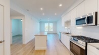Located at 6535 Alvarado Road in San Diego, CA, this thoughtfully designed one-bedroom, one-bathroom unit offers a clean, modern aesthetic throughout. The open-concept kitchen and living area serves as the heart of the home, featuring light wood-toned flooring that flows seamlessly across the entire space. The kitchen is well-appointed with sleek white cabinetry extending to the ceiling, stainless steel appliances including a gas range, built-in microwave, and side-by-side refrigerator, complemented by a white tile backsplash and a central island with counter seating. Recessed lighting illuminates the living area, which benefits from natural light through large windows with outdoor views of surrounding greenery. The bedroom is a comfortable, well-lit retreat with a ceiling fan, large windows, and direct access to a private balcony, bringing in additional natural light and outdoor connectivity. The bathroom features a full soaking tub and shower combo with elegant marble-style surround tiling, a built-in niche, and a curved chrome shower rod. A dedicated closet and hallway complete the layout, ensuring practical storage and smooth circulation throughout this bright, contemporary San Diego residence.