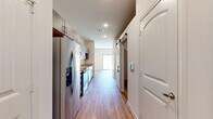 This thoughtfully designed single-floor residence combines modern finishes with a clean, functional layout. The kitchen is a standout feature, equipped with stainless steel appliances including a French door refrigerator, range, built-in microwave, and dishwasher. Granite countertops with speckled detailing complement the warm-toned wood cabinetry, while a stainless steel sink and ample upper and lower cabinet storage complete the space. Recessed lighting and light hardwood-style flooring run consistently throughout the home, creating a bright and cohesive aesthetic. A distinctive sliding barn door adds a contemporary architectural touch along the main hallway. The bathroom features matching granite countertops, dark wood cabinetry with modern hardware, an undermount sink, and a well-appointed vanity mirror with overhead storage. A spacious living area benefits from abundant natural light streaming through large sliding glass doors that open directly onto a private patio, offering views of a fenced outdoor yard. Additional rooms provide versatile, open spaces with neutral walls and consistent flooring, ready for a variety of uses. The overall ambiance is clean, modern, and move-in ready, reflecting thoughtful attention to material consistency and contemporary design throughout.
