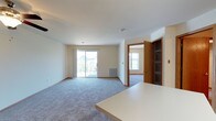 This single-floor residence offers a thoughtfully designed layout with a seamless flow between living, dining, and kitchen spaces. The open-concept living area is generously sized, featuring plush wall-to-wall carpeting, neutral-toned walls, and a ceiling fan with light fixture. A sliding glass door leads to a private balcony overlooking a well-maintained residential community, providing pleasant outdoor views of mature trees and landscaped grounds.

The kitchen is functionally designed with warm oak cabinetry, light countertops, and wood-look flooring. Stainless steel appliances include a refrigerator, electric range, and dishwasher. A peninsula island provides additional prep space and a natural transition into the living area.

The bedrooms are carpeted and bright, each featuring windows that bring in natural light. Hallways connect the rooms efficiently, with built-in shelving visible near entryway areas. The bathroom is clean and practical, featuring a full tub-shower combination, a wide vanity with ample cabinet storage, a large mirror, and wood-look tile flooring. Throughout the unit, warm wood-toned door frames and trim provide a cohesive, inviting aesthetic.