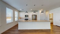 This single-floor space is designed with a clean, modern aesthetic and an open-concept layout that seamlessly connects the kitchen and living areas. Warm hardwood flooring runs throughout, providing visual continuity across all rooms.

The kitchen is a standout feature, equipped with white shaker-style cabinetry, a marble-style tile backsplash, and neutral-toned quartz countertops. A large central island with an integrated sink serves as both a functional workspace and a natural dividing point between the kitchen and living area. Stainless steel appliances, including a range, built-in microwave, and French door refrigerator, complete the kitchen. Industrial-style pendant lights hang above the island, adding a contemporary touch.

The living area is spacious and bright, benefiting from multiple windows that invite abundant natural light and offer views of the surrounding greenery. A set of glass doors provides additional outdoor access.

Bedrooms are well-proportioned, featuring ceiling fans, multiple windows, and walk-in closets with dual hanging rods. The bathrooms are finished with white cabinetry, quartz countertops, and hardwood-style flooring. The primary bathroom includes a double vanity with backlit mirrors and a soaking tub, while a secondary bathroom offers a glass-enclosed walk-in shower.
