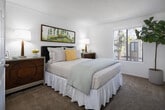 Located at 1942 Deerpark Dr in Fullerton, CA, this single-story home offers a thoughtfully arranged floor plan with a bright, cohesive design throughout. The living room is a standout space, showcasing vaulted ceilings with exposed wood beams and a sliding glass door that opens directly onto a private patio, allowing natural light to fill the room while providing outdoor access. The open layout connects the living area to the dining space, which features a ceiling fan, a large window overlooking the exterior, and wood-style flooring that continues into the kitchen.

The kitchen is well-equipped with white cabinetry, stone-toned countertops, a full suite of white appliances, recessed lighting, and a generous window that brings in additional natural light. The primary bedroom is carpeted and comfortably sized, with a window that lets in ample daylight. A second bedroom offers similar comfort with its own window and plush carpeting. The bathroom features white cabinetry, stone-toned countertops, a large vanity mirror, and wood-style flooring, maintaining the clean aesthetic found throughout the home.