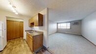 Located in Big Lake, Minnesota, this single-floor unit offers three bedrooms, one bathroom, a kitchen, a hallway, and a closet. The kitchen is equipped with warm wood-toned cabinetry, a double-basin sink with granite-look countertops, a dishwasher, and a full-size refrigerator. Wood-style flooring runs through the kitchen and dining area, while plush carpet covers the living room and all bedrooms. A ceiling fan with light fixture in the dining area adds comfort and airflow, complemented by track lighting over the kitchen. The generously sized living room benefits from natural light through a large window dressed with vertical blinds, and includes a wall-mounted air conditioning unit alongside baseboard heating for year-round climate control. The spacious primary bedroom offers ample room and a dedicated closet with hanging rod. The two additional bedrooms are carpeted and each include windows with blinds and baseboard heaters. The full bathroom features a clean, white tub-shower combination with chrome fixtures. Textured ceilings are present throughout the unit, lending a consistent finish. The overall layout is practical and well-organized, making efficient use of the available space.
