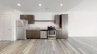 Located at 728 Market St in the heart of downtown Chattanooga, TN, this contemporary single-floor unit offers a thoughtfully designed open layout with modern finishes throughout. The kitchen is a standout feature, outfitted with dark espresso cabinetry, granite countertops, stainless steel appliances including a refrigerator, electric range, and dishwasher, all set atop light wood-style flooring that flows seamlessly through the main living areas. The bright and airy living room is bathed in natural light from large black-framed windows and a sliding glass door that opens to a private balcony, offering impressive views of the downtown Chattanooga skyline. The unit includes two bathrooms, each finished with granite-topped dark vanities and tile flooring. The full bathroom features a tub-shower combo with subway tile surround, while the second bathroom offers a vanity with ample cabinet storage. The bedroom is carpeted and well-lit with natural light from a city-facing window, complemented by a closet. Clean white walls, modern hardware, and consistent finishes throughout give this space a cohesive, contemporary aesthetic well-suited for urban living in one of Chattanooga's most vibrant districts.