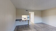 Located in Orlando, FL, this compact and functional one-bedroom, one-bathroom unit offers a practical single-floor layout thoughtfully designed to maximize every square foot. The open-concept living and dining area features durable wood-style plank flooring and neutral warm-toned walls, creating a clean and versatile backdrop. A front window allows natural light to fill the space and provides views of the surrounding greenery. The kitchen is connected via a peninsula-style breakfast bar with a granite-patterned countertop and bar seating, offering a convenient pass-through view into the living area. The kitchen itself includes white appliances and ample counter space. A textured ceiling is consistent throughout the main living areas. The bedroom is carpeted for added comfort and features a sliding glass door that opens to an outdoor view, as well as access to a dedicated closet. The full bathroom includes a tub-shower combination with clean white fixtures and wood-style flooring. A dedicated closet provides additional storage. The unit's straightforward layout and practical finishes make it a well-organized and easy-to-maintain living space in the Orlando area.