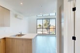 Located at 1740 Van Ness Ave in Fresno, CA, this two-story residence offers a thoughtfully designed layout spread evenly across two floors. The main level features a combined dining room, kitchen, and living area that creates a seamless open-concept space. The kitchen is outfitted with light wood-toned cabinetry, a stainless steel refrigerator, electric range with overhead ventilation, a stainless sink set into a clean white countertop peninsula, and a wall-mounted mini-split climate system. Large floor-to-ceiling windows flood the living area with natural light and provide open views of the surrounding neighborhood. Light wood-style flooring runs throughout both floors, contributing to the bright, airy aesthetic. A pantry adds practical storage to the main level. Upstairs, two bedrooms offer comfortable retreats, each equipped with wall-mounted mini-split units and sliding closet doors. The spacious primary bedroom features a ceiling fan and a wide window overlooking the outdoors. The full bathroom includes a tiled tub-shower combination, a pedestal sink, and wood-style flooring. The home's clean, contemporary design is defined by crisp white walls, modern finishes, and an abundance of natural light throughout.