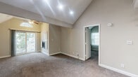 Located at 201 Kingstowne Rd in Newport News, Virginia, this two-story, one-bedroom, one-bathroom home offers a thoughtful layout spread across two levels. The main floor serves as the heart of the home, anchored by an open-concept kitchen and living area. The kitchen is well-appointed with crisp white cabinetry, dark marble-style countertops, a breakfast bar peninsula, and wood-look flooring — fully equipped with black appliances including a refrigerator, range, and microwave. The living room features plush carpeting, a ceiling fan, a fireplace, and soaring vaulted ceilings with recessed lighting that create an airy, open feel. Natural light filters in through multiple windows with views of the surrounding neighborhood. A full bathroom on the main level includes a tub-shower combination, vanity with white cabinetry, and wood-look flooring. Upstairs, accessed by a carpeted staircase with a sleek metal railing, the private bedroom offers dual corner windows, vaulted ceilings, plush carpet, and direct access to the bathroom. Three closets — including a spacious walk-in with wire shelving — provide excellent storage. A dedicated laundry area completes this well-organized home.