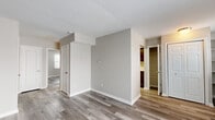 Located at 7601 Carlton Arms Dr in Indianapolis, Indiana, this single-floor, 2-bedroom, 1-bathroom residence offers a practical and well-appointed layout. Throughout the unit, wood-look luxury vinyl plank flooring provides a cohesive, modern aesthetic complemented by neutral gray and taupe wall tones and textured ceilings.

The living room is a bright, open space anchored by a sliding glass door fitted with vertical blinds, allowing generous natural light and providing access to an outdoor area. A side window further enhances the airy feel of the room.

The kitchen features rich, dark-stained cabinetry paired with crisp white countertops, a stainless steel sink with a brushed nickel faucet, and updated appliances including a black refrigerator and stainless dishwasher. Light-toned vinyl flooring ties the space together cleanly.

The primary bedroom is a well-sized retreat with a walk-in closet offering a curved rod system for organized storage. The secondary bedroom includes a standard sliding-door closet and a bright window with blinds. Both rooms continue the consistent wood-look flooring found throughout.

The bathroom is finished with a full tub-shower combination with white tile surround, a dark-stained vanity with a white countertop, and wood-look flooring, maintaining the unit's unified design language.