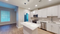 Located at 2008–2032 N Beauregard St in Alexandria, Virginia, this single-floor residence offers a clean, contemporary design with a neutral color palette and wood-look flooring that flows consistently throughout the space. The open-concept layout connects the living area to a well-equipped kitchen, creating a bright and functional shared space anchored by a central island with white quartz countertops. The kitchen features white shaker-style cabinetry extending to the ceiling, a subway tile backsplash, stainless steel appliances including a range, microwave, dishwasher, and refrigerator, and pendant lighting above the island. Natural light enters the living area through multiple windows fitted with horizontal blinds.

The bedrooms are generously proportioned, with large windows that allow ample natural light. One bedroom includes a walk-in closet with wire shelving on both sides, providing substantial storage. An additional bedroom features louvered double closet doors and recessed lighting. The bathrooms maintain the unit's clean aesthetic, with one offering a soaking tub and large-format tile surround, and another featuring a glass-enclosed walk-in shower with floor-to-ceiling tile. Light wood-tone flooring and white trim complete the cohesive, modern interior throughout.