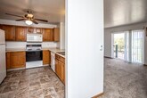This single-floor unit is organized around a practical, open-concept layout that connects the kitchen and living areas seamlessly. The kitchen is equipped with warm oak cabinetry extending to the upper walls, a white electric range, microwave, refrigerator, and a double sink set into a peninsula counter. Tile flooring in a stone-like pattern runs throughout the kitchen, providing a durable and easy-to-maintain surface. A ceiling fan overhead adds air circulation to the space.

The living area flows directly from the kitchen and features neutral carpet, white walls, and a sliding glass door that opens to a private balcony, allowing natural light and outdoor views into the room. A wall-mounted air conditioning unit serves the living space. The bedroom is carpeted and comfortably sized, with a ceiling fan, a wall A/C unit, a baseboard heater, and a window offering natural light and exterior views.

The bathroom includes tile flooring, a full tub and shower combination with a chrome curtain rod, a toilet, and a wood-toned vanity. Throughout the unit, clean white walls and consistent finishes contribute to a straightforward, functional ambiance.