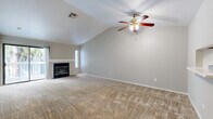 Located at 1100 E Leland Rd in Pittsburg, CA, this single-story residence offers three bedrooms and two bathrooms across a thoughtfully laid-out floor plan. The open-concept living and dining area serves as the heart of the home, highlighted by soaring vaulted ceilings, a ceiling fan with light fixture, and a classic fireplace framed by a clean white mantel. A sliding glass door opens to a private balcony, allowing natural light to fill the space and providing pleasant outdoor views. Neutral-toned carpet runs throughout the living areas and bedrooms, creating a warm and cohesive feel. The galley-style kitchen features warm wood cabinetry, white appliances including an electric range and refrigerator, a stainless steel sink with light countertops, and hardwood-style flooring that extends into the bathrooms. The primary bedroom offers a comfortable footprint with a natural window view. The two additional bedrooms are well-sized, each with windows providing natural light. Both bathrooms are finished with oak-toned vanities, white countertops, and hardwood-style flooring — one featuring a walk-in shower with sliding glass doors and the other a full tub/shower combo. A dedicated laundry area and utility room add everyday convenience to this well-appointed home.