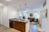 Located at 305 E Front St in downtown Missoula, Montana, this modern 4-bedroom, 4-bathroom unit offers a well-designed single-floor layout. The open-concept kitchen and living area serves as the heart of the space, where a peninsula kitchen with rich wood-finish cabinetry, granite countertops, pendant lighting, and black appliances flows seamlessly into the combined dining and living room. Wood-plank flooring runs throughout the main living area, while a ceiling fan and large windows with blinds allow ample natural light to fill the space. The kitchen also features a pantry and dedicated laundry area for added convenience. Each of the four bedrooms is thoughtfully sized, carpeted, and equipped with its own closet, large windows offering outdoor views, and direct access to a private bathroom. The four bathrooms are consistently finished with wood-tone vanity cabinetry, granite countertops, large mirrors, and tub-shower combinations. A hallway connects the private bedrooms to the shared living spaces, contributing to a functional and organized floor plan. The clean white walls, consistent modern finishes, and well-distributed natural light throughout give the unit a bright, contemporary ambiance well-suited for shared or individual living in the heart of Missoula.