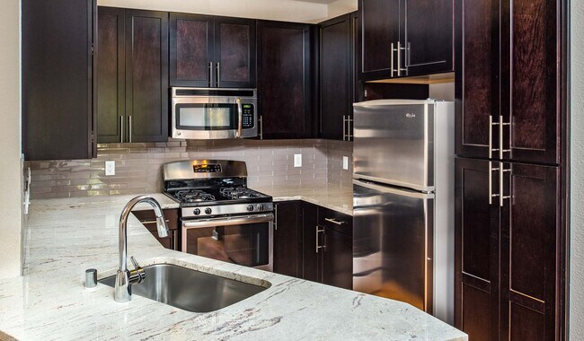 Cocina moderna con electrodomésticos de acero inoxidable, encimeras de granito y gabinetes de primera calidad. - Monterey Grove