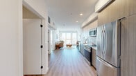 Located in the vibrant Mid-City neighborhood of Los Angeles, this well-appointed 2-bedroom, 1-bathroom residence offers a thoughtfully designed single-floor layout with modern finishes throughout. Light wood-tone flooring flows seamlessly across the open-concept living space, creating a warm and cohesive aesthetic.

The kitchen is outfitted with light wood cabinetry, white quartz countertops, a tile backsplash, and a full suite of stainless steel appliances including a refrigerator, range, microwave, and dishwasher. It opens directly into the dining and living area, making the space ideal for entertaining.

The living room is bright and welcoming, with large sliding glass doors leading to a private balcony that brings in generous natural light and offers open city views. The spacious primary bedroom features a large window with additional outdoor views, while the second bedroom provides a comfortable and versatile space. A dedicated closet and in-unit laundry add practical convenience.

The bathroom is finished with large-format marble-look tile flooring and includes a full soaking tub with a shower. Clean white walls and recessed lighting throughout the unit contribute to a crisp, contemporary ambiance. A hallway with additional storage connects the rooms with ease.