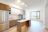 This thoughtfully designed one-bedroom, one-bathroom residence in Washington, DC offers a modern aesthetic and efficient use of space throughout. The open-concept kitchen, dining, and living area forms the heart of the home, bathed in natural light from large floor-to-ceiling windows that frame sweeping city views. The kitchen is a standout feature, showcasing two-tone cabinetry with warm wood lower cabinets and crisp white upper cabinets, a textured tile backsplash, stainless steel appliances including a Bosch range and built-in microwave, and a sleek center island with additional storage — ideal for both cooking and casual dining. Light hardwood flooring flows seamlessly throughout the living areas, enhancing the bright, airy atmosphere. The bedroom is generously proportioned, featuring large windows that continue the abundance of natural light and offer outdoor views. Two closets provide ample storage. The bathroom is finished with neutral large-format floor tiles, a full soaking tub with tiled surround, and clean, contemporary fixtures. A dedicated laundry area adds everyday convenience. The overall design is clean and modern, with a consistent palette of white walls, warm wood tones, and quality finishes throughout.