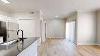 Located at 7550 S Blackhawk St in Englewood, Colorado, this thoughtfully designed one-bedroom, one-bathroom residence offers an efficient and comfortable single-floor layout. Light-toned luxury vinyl plank flooring flows throughout the main living areas, complemented by neutral warm-gray walls and crown molding that lend a clean, polished aesthetic.

The open-concept living room is bright and airy, featuring a sliding glass door with vertical blinds that opens to an outdoor area and allows generous natural light. A large window provides additional views of the surrounding neighborhood.

The kitchen is well-equipped with crisp white cabinetry, gray quartz countertops, a peninsula with a undermount sink and matte black faucet, and a full suite of stainless steel appliances including a refrigerator, range, and built-in microwave.

The bedroom is carpeted for comfort, features a ceiling fan, a window with natural light, and direct access to a dedicated walk-in closet outfitted with wire shelving and organizational racks. The bathroom includes a soaking tub with white tile surround accented by a teal tile border. An in-unit laundry area adds everyday convenience, rounding out this functional and move-in-ready residence.