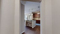 This single-story residence offers a thoughtfully designed layout across two bedrooms and two bathrooms. The open-concept kitchen and living area serves as the heart of the home, where rich, dark hardwood-style flooring flows throughout. The kitchen is well-equipped with stainless steel appliances, dark wood cabinetry, granite-style countertops, and a breakfast bar with pendant lighting overhead—ideal for casual dining or entertaining.

The living room features crown molding, a ceiling fan, and access to natural light through sliding glass doors framed by stylish drape panels. Both bedrooms are carpeted and include windows that bring in natural light and outdoor views, with each room serviced by its own dedicated closet featuring wire shelving systems. The primary bedroom includes a walk-in closet with ample hanging and storage space.

Each bathroom is finished with dark wood vanities, light countertops, and hardwood-style flooring. One bathroom includes a full tub-shower combination with white tile surround, while the other provides direct access to the primary closet. Neutral wall tones and consistent finishes throughout create a cohesive and polished ambiance.