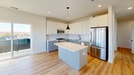 This well-appointed 2-bedroom, 2-bathroom home in Carteret, NJ offers a thoughtfully designed single-floor layout with modern finishes throughout. Light wood-tone flooring flows seamlessly across the space, complementing the clean white walls and creating a bright, cohesive aesthetic.

The open-concept living, dining, and kitchen area serves as the heart of the home. The kitchen is a standout feature, showcasing two-tone cabinetry — white upper cabinets paired with soft blue-grey lowers — white subway tile backsplash, a central island with a white countertop, stainless steel appliances, and stylish black pendant lighting. The space opens naturally into the living and dining areas, promoting an easy, connected flow.

The primary bedroom is generously sized and features sliding glass doors that lead to a private balcony with outdoor views. The second bedroom is comfortably scaled with a large window allowing ample natural light. Both bedrooms benefit from multiple closets for plentiful storage.

The primary bathroom is elegantly finished with full white tile, a glass-framed walk-in shower, dual vanity sinks, and matte black hardware accents. The second bathroom maintains the same clean, modern palette with a single vanity and large-format tile flooring.

Additional highlights include a dedicated laundry area, utility room with electrical panel, entrance foyer, and hallway connecting all spaces efficiently.