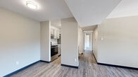 This 2-bedroom, 2-bathroom residence offers a thoughtfully designed single-floor layout that balances comfort and functionality. The open living room serves as the heart of the home, highlighted by a striking floor-to-ceiling white-painted brick fireplace and a wide window that invites natural light and outdoor views. Durable wood-look flooring runs throughout the main living areas, lending a clean, contemporary feel.

The kitchen is efficiently appointed with gray shaker-style cabinetry, granite countertops, a peninsula with an integrated sink, and stainless steel appliances including a refrigerator and range with overhead ventilation. A hallway connects the living and kitchen areas to the private sleeping quarters.

Both bedrooms are carpeted for warmth and comfort. The primary bedroom offers generous proportions with a window for natural light. The second bedroom also features a window with exterior views. A dedicated closet provides built-in shelving and hanging space for organized storage.

The two bathrooms are well-finished: one features a sliding-door glass shower enclosure with a granite vanity, while the second offers a full tub-shower combination with white tile surround and a matching granite-topped vanity. Neutral tones throughout the space create a clean, move-in ready environment.