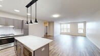 Located at 1850 Green Bay Rd in Highland Park, IL, this generously sized 5-bedroom, 3-bathroom residence offers an expansive, single-floor layout designed for comfortable living. The open-concept kitchen is a standout feature, boasting slate-gray shaker cabinetry with gold hardware, a large quartz-topped center island, a chevron-patterned tile backsplash, stainless steel appliances, and bold black pendant lighting overhead. Hardwood-style flooring flows throughout the main living areas, adding warmth and continuity to the space. The five bedrooms offer a mix of hardwood-style and plush carpeted flooring, with several rooms featuring multiple windows that invite ample natural light. The generously sized primary bedroom includes a well-appointed walk-in closet with built-in shelving, hanging rods, and dedicated storage sections. Three full bathrooms are finished with clean, modern tile work and frameless glass-enclosed walk-in showers with rain showerheads. One bathroom features an ADA-accessible shower with safety grab bars. The dedicated laundry room impresses with matching gray cabinetry, a quartz countertop, an under-counter sink, and in-unit washer. With four closets throughout, storage is plentiful. The overall aesthetic is clean, contemporary, and move-in ready.