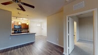This single-floor residence in Jacksonville, Florida offers a well-designed open-concept layout that seamlessly connects the main living areas. The spacious living room features rich, dark hardwood-style flooring and a ceiling fan, with large windows that invite abundant natural light and offer views of the surrounding greenery. An elegant chandelier anchors the adjacent dining area, which flows naturally into the kitchen.

The kitchen is thoughtfully appointed with rich wood cabinetry, a decorative tile backsplash, granite-style countertops, and black appliances including a range, microwave, and refrigerator. Track lighting and pendant lights illuminate the space, while a peninsula with a sink provides additional workspace and a casual dining option. Light tile flooring extends throughout the kitchen.

The bedrooms are generously proportioned, each featuring plush carpet, ceiling fans, and windows with views of the lush exterior landscape. The primary bathroom includes a wide vanity with rich wood cabinetry, a large mirror, and a separate shower enclosure. The secondary bathroom offers a full tub-shower combo with tile surround and light tile flooring throughout. This residence combines functional design with quality finishes for comfortable everyday living.
