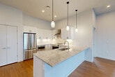 This well-designed 3-bedroom, 2-bathroom residence in Natick, MA offers a thoughtfully laid-out single-floor plan with modern finishes throughout. The centerpiece of the home is the open-concept kitchen, which features crisp white shaker cabinetry, a large granite-topped island with an undermount sink, stainless steel appliances including a French door refrigerator and range with hood, and elegant pendant lighting — all set over warm hardwood flooring. The kitchen flows seamlessly into the dining and living areas, creating an ideal space for everyday living and entertaining. The three bedrooms are carpeted and filled with natural light from large windows that offer views of the surrounding Natick neighborhood. The primary bedroom provides a comfortable and spacious retreat. Both bathrooms are finished with clean, contemporary fixtures; one features a walk-in glass-enclosed shower with white tile surround and a white vanity with under-cabinet storage, while the second offers a bright, minimalist design with large-format floor tile and a floating vanity. Three closets provide ample storage throughout. The home's neutral color palette, recessed lighting, and modern detailing create a fresh and move-in-ready atmosphere.