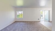 This single-floor unit in Arlington, Washington presents a well-designed, move-in-ready layout with a consistent, modern aesthetic throughout. The open living area is carpeted in neutral-toned plush carpet and features multiple windows that allow ample natural light to fill the space, along with access to an outdoor balcony that extends the living area and provides views of the surrounding greenery.

The kitchen is efficiently laid out with white shaker-style cabinetry, white quartz countertops, a peninsula with a sink, and stainless steel appliances including a refrigerator and electric range. Wood-look vinyl plank flooring runs through the kitchen, adding warmth and durability.

The bedrooms are generously proportioned, each featuring plush carpet, white walls, and good natural light. Closet space is provided in the bedrooms, with double doors offering organized storage. The bathrooms are finished in a clean, all-white palette, featuring tub/shower combinations, white vanities with undermount sinks, brushed nickel fixtures, and wood-look flooring. The overall ambiance of the unit is bright, clean, and functional, reflecting contemporary residential design throughout.