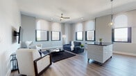 Located at 157 S Main St in the heart of downtown Akron, Ohio, this single-floor unit offers a well-designed layout with contemporary finishes throughout. The open living area is anchored by large arched-top windows that frame striking city views, flooding the space with natural light. Light-toned hardwood-style flooring, a ceiling fan, and neutral walls contribute to a clean, modern aesthetic throughout the main living zone.

The kitchen is outfitted with sleek white flat-front cabinetry, dark countertops, a glossy white subway tile backsplash, and a full suite of stainless steel appliances, including a dishwasher, range, and microwave. Arched windows in the kitchen also provide elevated views of the surrounding cityscape. Adjacent to the living area, a dedicated dining space features warm hardwood-style flooring and a contemporary pendant light fixture.

The unit includes two bedrooms, each with plush carpeting and organized closet systems. The primary bedroom benefits from arched windows with city views, while the secondary bedroom offers a quiet, efficiently arranged layout. The bathroom is finished with light tile flooring, a wall-mounted vanity, large mirror, and a glass-enclosed shower area, maintaining the unit's clean, modern character throughout.