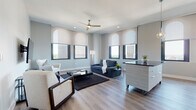 Located at 157 S Main St in the heart of downtown Akron, Ohio, this single-floor unit offers a well-designed layout with contemporary finishes throughout. The open living area is anchored by large arched-top windows that frame striking city views, flooding the space with natural light. Light-toned hardwood-style flooring, a ceiling fan, and neutral walls contribute to a clean, modern aesthetic throughout the main living zone.

The kitchen is outfitted with sleek white flat-front cabinetry, dark countertops, a glossy white subway tile backsplash, and a full suite of stainless steel appliances, including a dishwasher, range, and microwave. Arched windows in the kitchen also provide elevated views of the surrounding cityscape. Adjacent to the living area, a dedicated dining space features warm hardwood-style flooring and a contemporary pendant light fixture.

The unit includes two bedrooms, each with plush carpeting and organized closet systems. The primary bedroom benefits from arched windows with city views, while the secondary bedroom offers a quiet, efficiently arranged layout. The bathroom is finished with light tile flooring, a wall-mounted vanity, large mirror, and a glass-enclosed shower area, maintaining the unit's clean, modern character throughout.