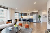 Located at 16505 Redmond Way in Redmond, WA, this well-appointed 2-bedroom, 2-bathroom residence offers a thoughtfully designed single-level layout with a clean, modern aesthetic. The open-concept living, dining, and kitchen area serves as the heart of the home, bathed in natural light from expansive floor-to-ceiling windows that frame views of the surrounding neighborhood. Light wood-tone flooring runs throughout, creating a warm and cohesive feel.

The contemporary kitchen is equipped with stainless steel appliances, including a refrigerator, dishwasher, and range, complemented by dark wood cabinetry, white quartz countertops, and a central island with bar seating. A dedicated dining area flows naturally from the kitchen into the spacious living room, which features a wall-mounted mini-split system for climate control.

The primary bedroom is generously sized, offering large windows with outdoor views and a sliding-door closet. The second bedroom provides a comfortable retreat with its own closet space. Both bathrooms are finished with white subway tile, quartz vanities, and dark wood cabinetry. A clean, minimalist entrance with a built-in mirror welcomes residents home. Four closets throughout the residence provide ample storage.